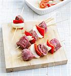 Pricking the meat,onions and peppers onto the wooden brochettes