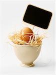 Egg in straw in a small bowl with a small sign