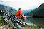 Mature Man Sitting by Lake with Mountain Bike, Vilsalpsee, Tannheim Valley, Tyrol, Austria