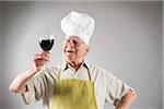 Senior Man with Red Wine wearing Apron and Chef's Hat, Studio Shot