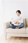 Young woman in a white shirt sitting on sofa