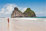 South America, Brazil, Pernambuco, Fernando de Noronha Island, a girl walking along Father's Well beach in front of the Two Brothers Rocks (Morro Dois Irmaos) MR