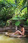 Dominica, Roseau. A young woman relaxes in the natural springs at Papillote Wilderness Retreat. (MR).