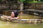 Dominica, Roseau. A young woman relaxes in the natural springs at Papillote Wilderness Retreat. (MR).