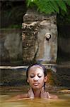 Dominica, Roseau. A young woman relaxes in the natural springs at Papillote Wilderness Retreat. (MR).