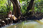 Dominica, Portsmouth. A young woman sits by the Indian River, one of Dominica's most popular tourist attractions. (MR).