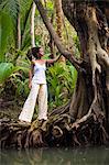 Dominica, Portsmouth. A young woman stands on a tree on the Indian River, one of Dominica's most popular tourist attractions. (MR).