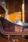 Dominica, Portsmouth, Tanetane. A young lady reads whilst laying on a Chaise Lounge at Manicou River Resort.(MR).