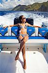 Dominica, Soufriere. A young woman sunbathes on the back of a Powerboat near Soufriere. (MR).