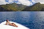 Dominica, Soufriere. A young woman sunbathes on the foredeck of a Powerboat near Soufriere. (MR).