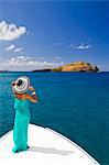 Dominica, Soufriere. A young woman stands on the foredeck of a Powerboat near Soufriere, looking at Scott's Head - a distinctive landmark of Dominica. (MR).