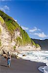 Dominica, Riviere Cyrique. A young woman walks along the black sand beach at Wavine Cyrique. (MR).