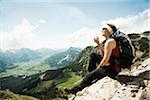 Mature woman sitting on cliff, hiking in mountains, Tannheim Valley, Austria