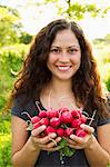 Portrait of young woman holding crop of radishes in allotment