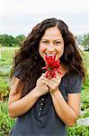 Portrait of young woman holding  crop of red chillies in allotment