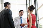 Mature doctor shaking hands with young couple in hospital lobby