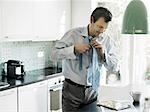 Mature businessman getting ready and using tablet in kitchen