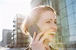 Mid adult woman using cellphone in sunlight outdoors