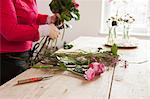 Close up of young woman arranging fresh flowers into bouquet