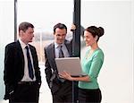 Three colleagues talking, woman holding laptop