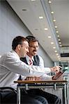 Two businessmen looking and pointing at digital tablet