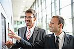 Businessmen pointing and looking at wall screen