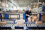 Male warehouse worker packing cardboard boxes for conveyer belt