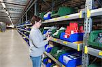 Female warehouse worker selecting item from shelving