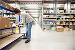 Female warehouse worker checking orders on delivery trolley