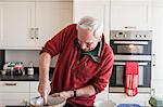 Senior male using wooden spoon in mixing bowl