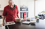 Senior male studying recipe on kitchen counter