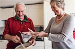 Senior couple sieving flour into mixing bowl