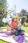 Mother and daughter sitting on blanket in garden with pinwheel