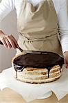 Woman spreading melted chocolate on cake