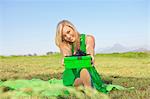 Woman sitting in field offering green gift