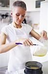 Woman pouring cake mixture into cake tin