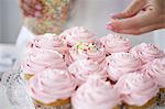 Woman decorating cupcakes with sugar sprinkles