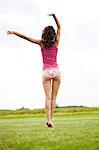 Young woman in a field, rear view, oudoors