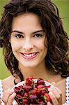 Young woman holding a bowl of red fruits, oudoors