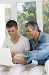 Senior man an young man at home, using laptop