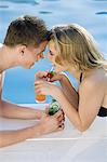 Young couple near a pool, cocktails