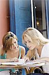 Two young women looking at a map, sitting at coffee shop terrace