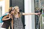 Two young women looking at show window