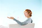 Portrait of woman on light blue background, playing with bubbles