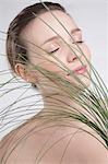 Portrait of young woman holding plants in front of her face