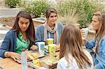 Teenagers drinking some soft drink and eating an hamburger