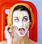 Portrait woman, towel on hair, face pack, putting cucumber slices on face