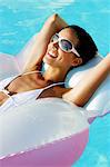 Portrait woman smiling, sunbathing, lying on air bed in swimming pool
