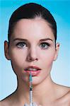 Young woman with syringe on lips