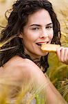 Young woman in wheat field, eating a rusk